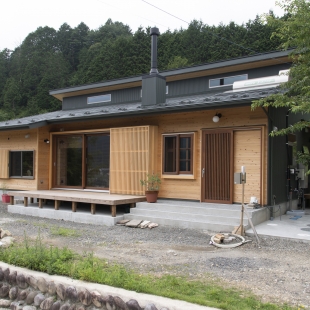 山を背にした、薪ストーブのある平屋