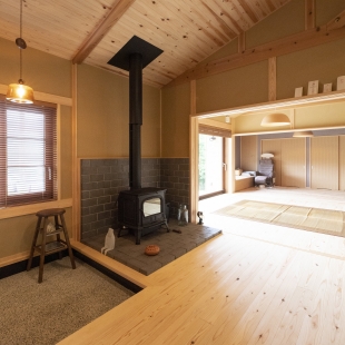 山を背にした、薪ストーブのある平屋
